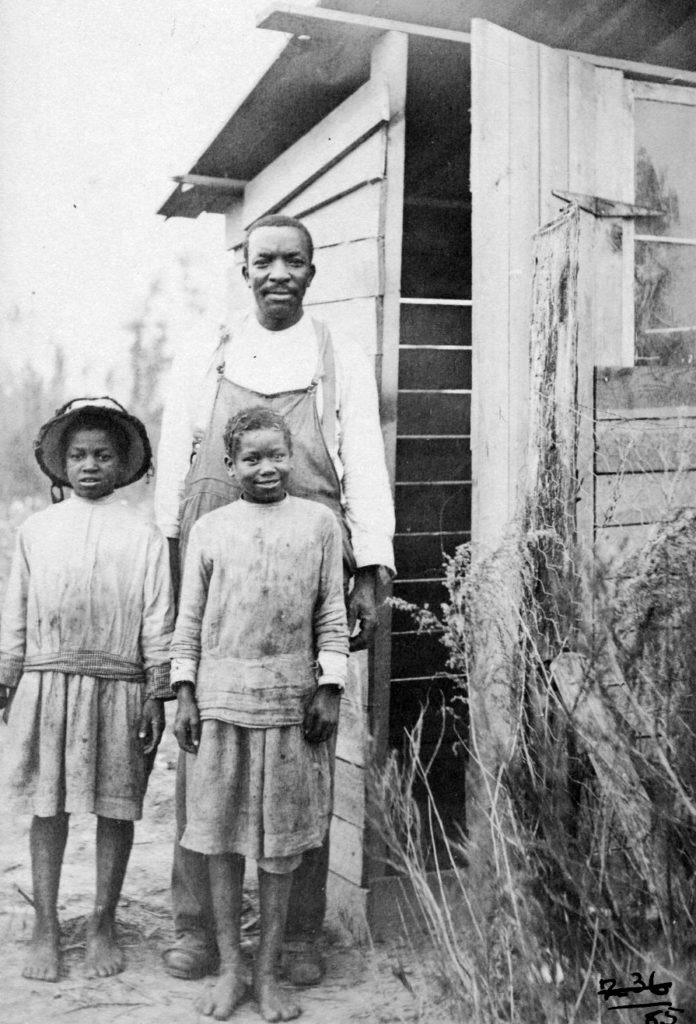 Black and white image of a family on front of their new privy.