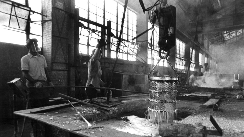 Black and white photo of a Hubbard and Co., a manufacturing business in Emeryville, California. Featured are two employees using equipment to produce hardware.