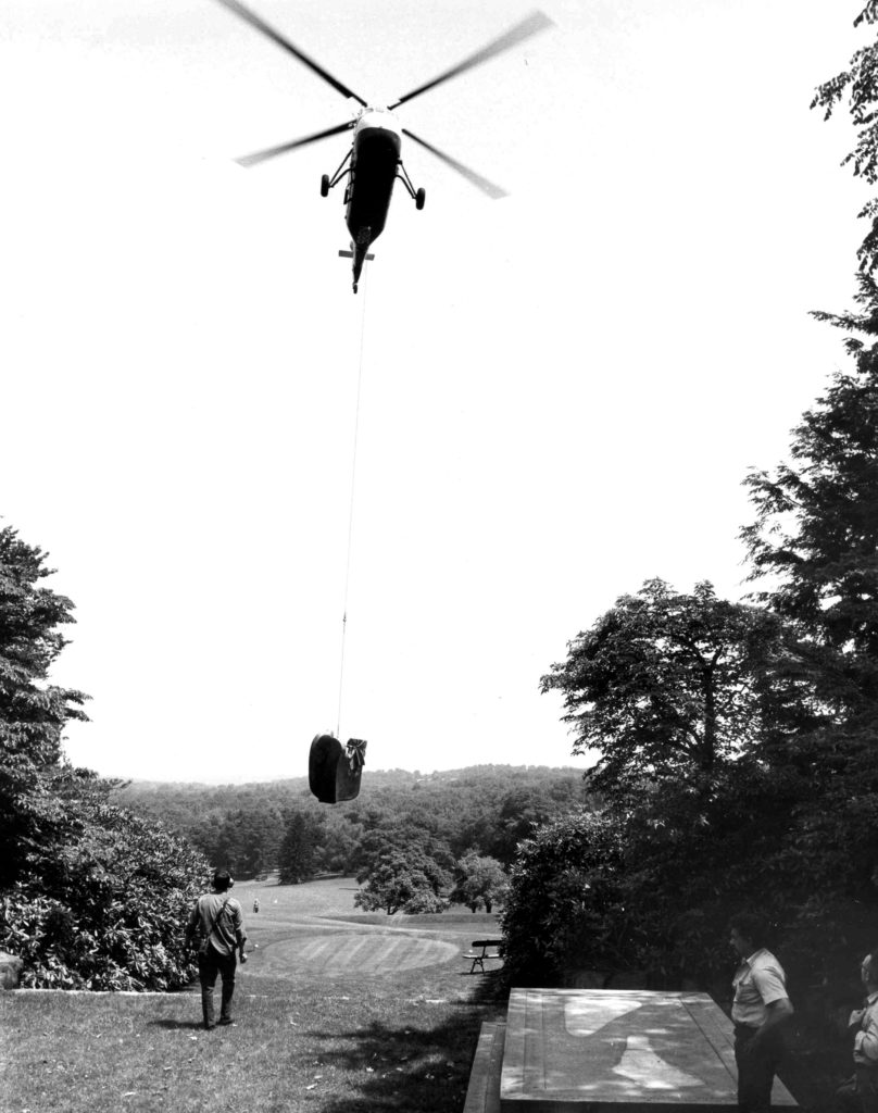 Black and white photo of a helicopter placing an outdoor sculpture from Nelson’s Kykuit estate.