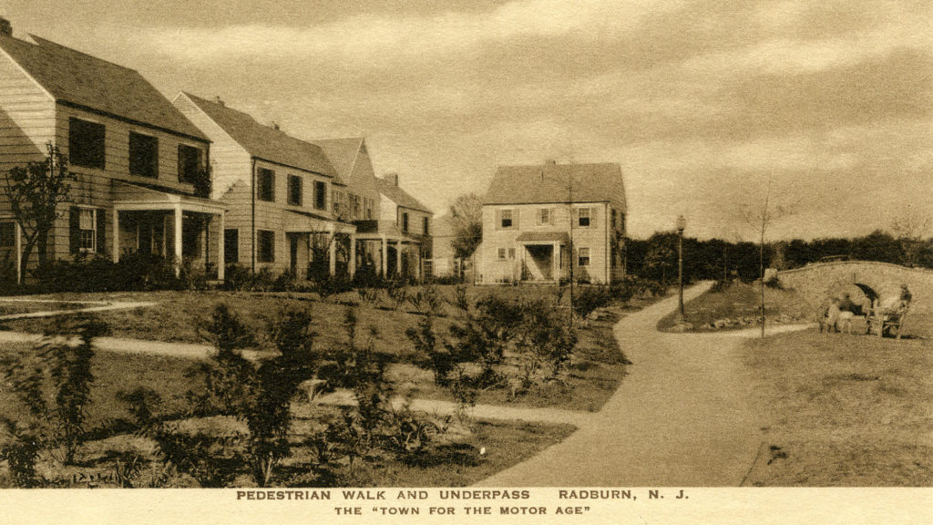 Image of Radburn, New Jersey with houses on the left side of the photo with pedestrian walkways, with an underpass on the right. The photo reads "Pedestrian walk and underpass Radburn, N.J., The "Town for the Motor Age".
