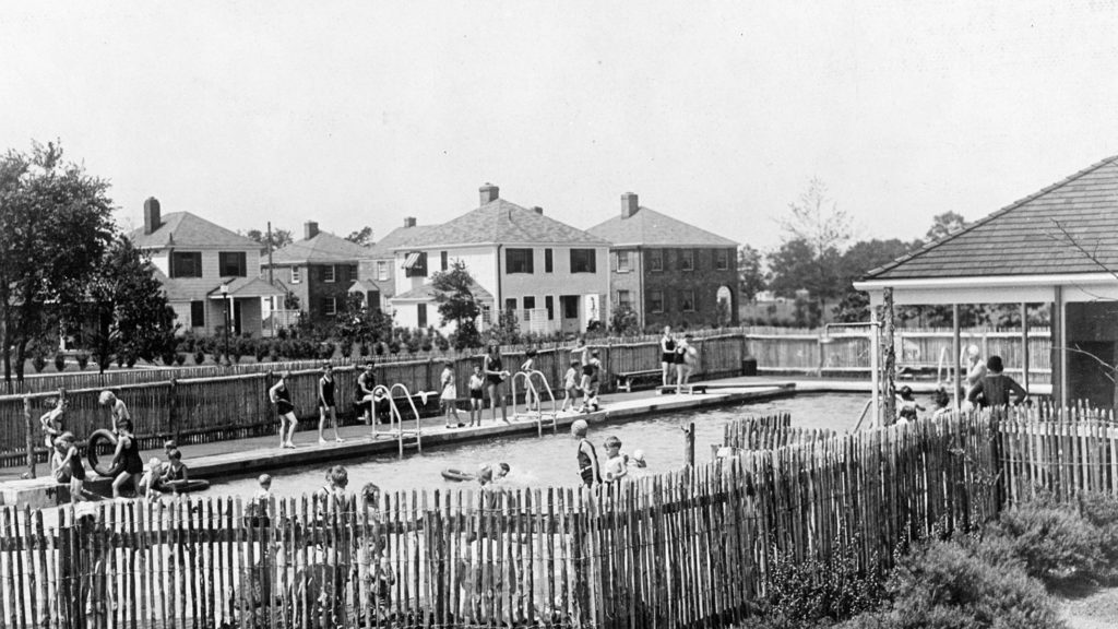 Black and white photo of a swimming pool in Radburn, New Jersey. Pool is fenced off with multiple swimming.