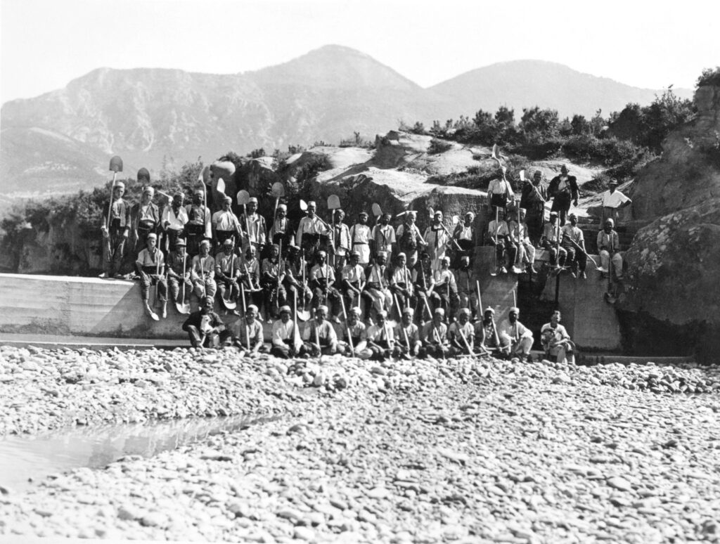 A grayscale group photo of the team carrying out canal clearance work posing with shovels.
