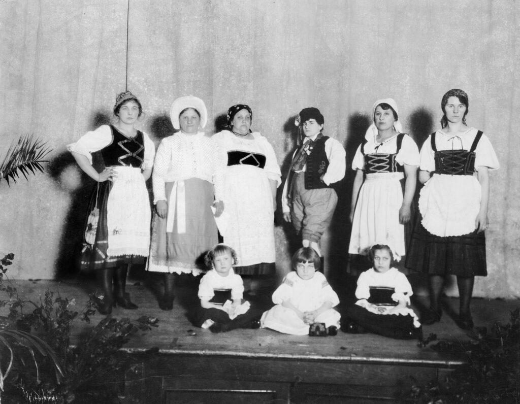 Six eastern European women and three young girls stand for a portrait, all in native dress.